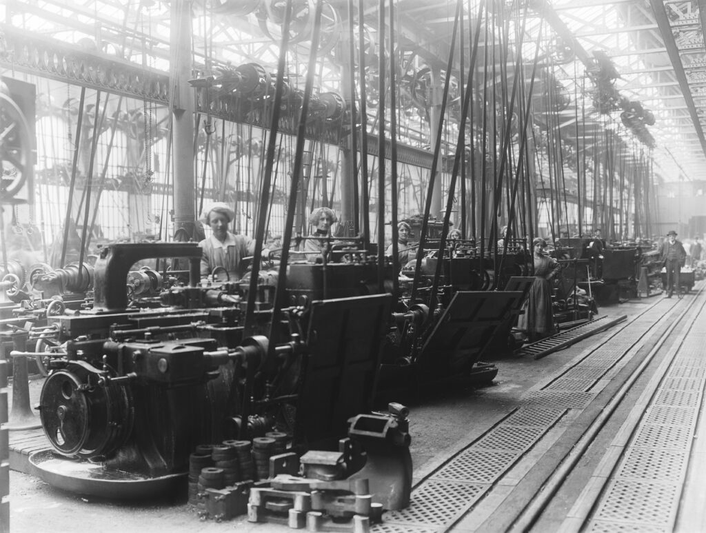 A black and white photograph of women at a row of automatic machinery.